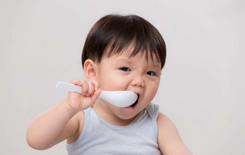 Toddler feeding self with spoon