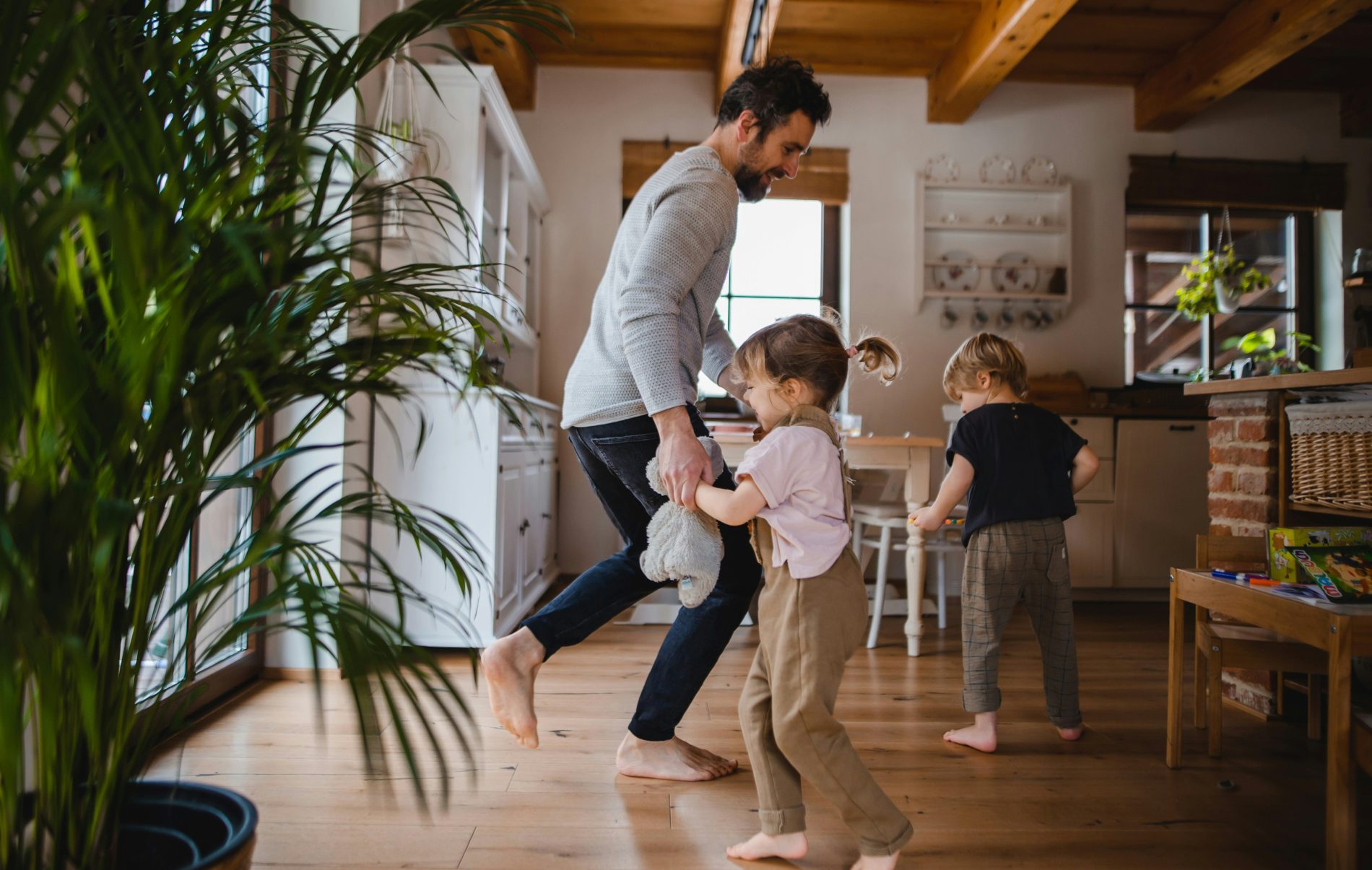 Parent and young children dancing barefoot in the kitchen, helping a child unwind after school through playful movement and connection