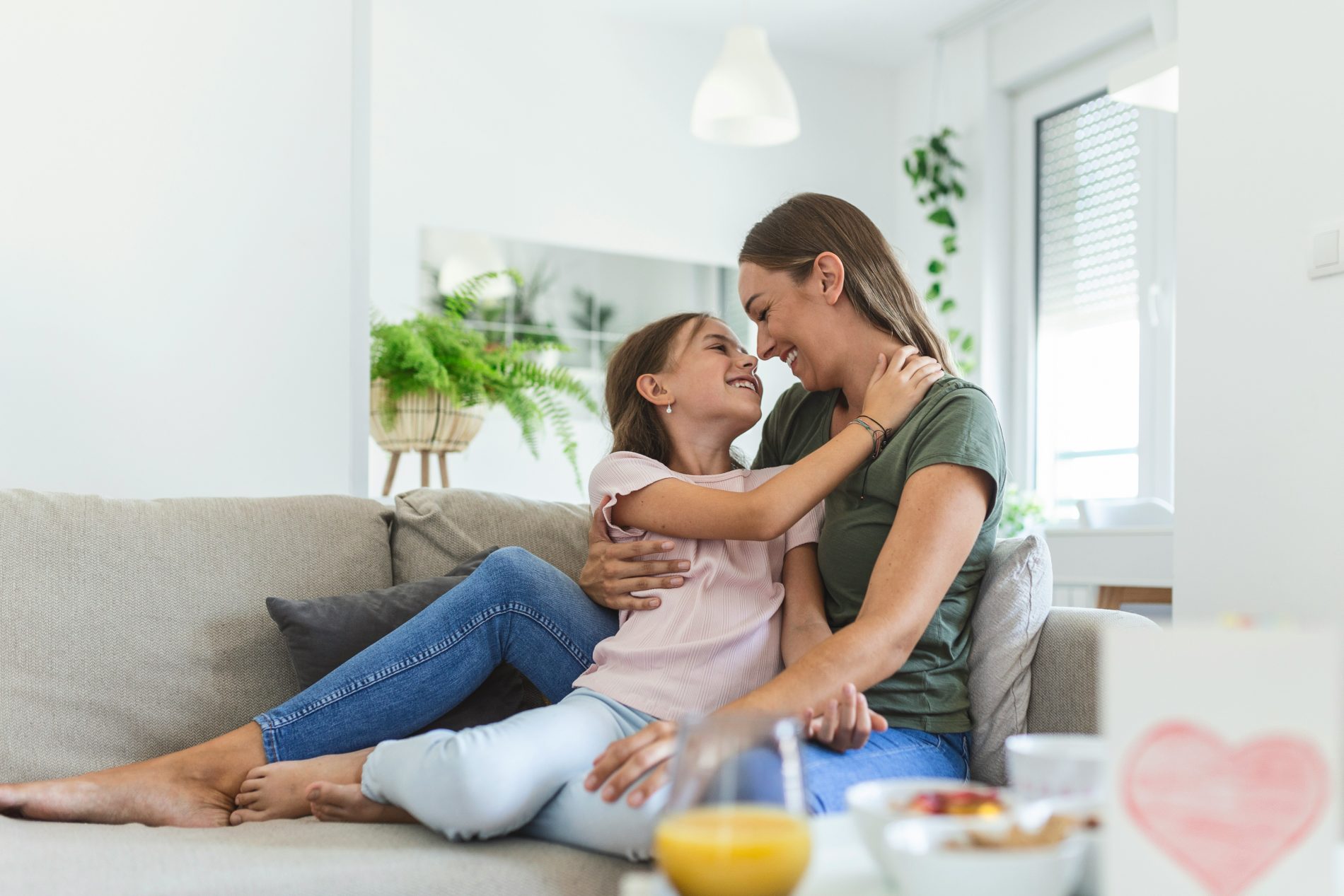 Mother hugging daughter on couch to support calming down after school and helping a child unwind after school