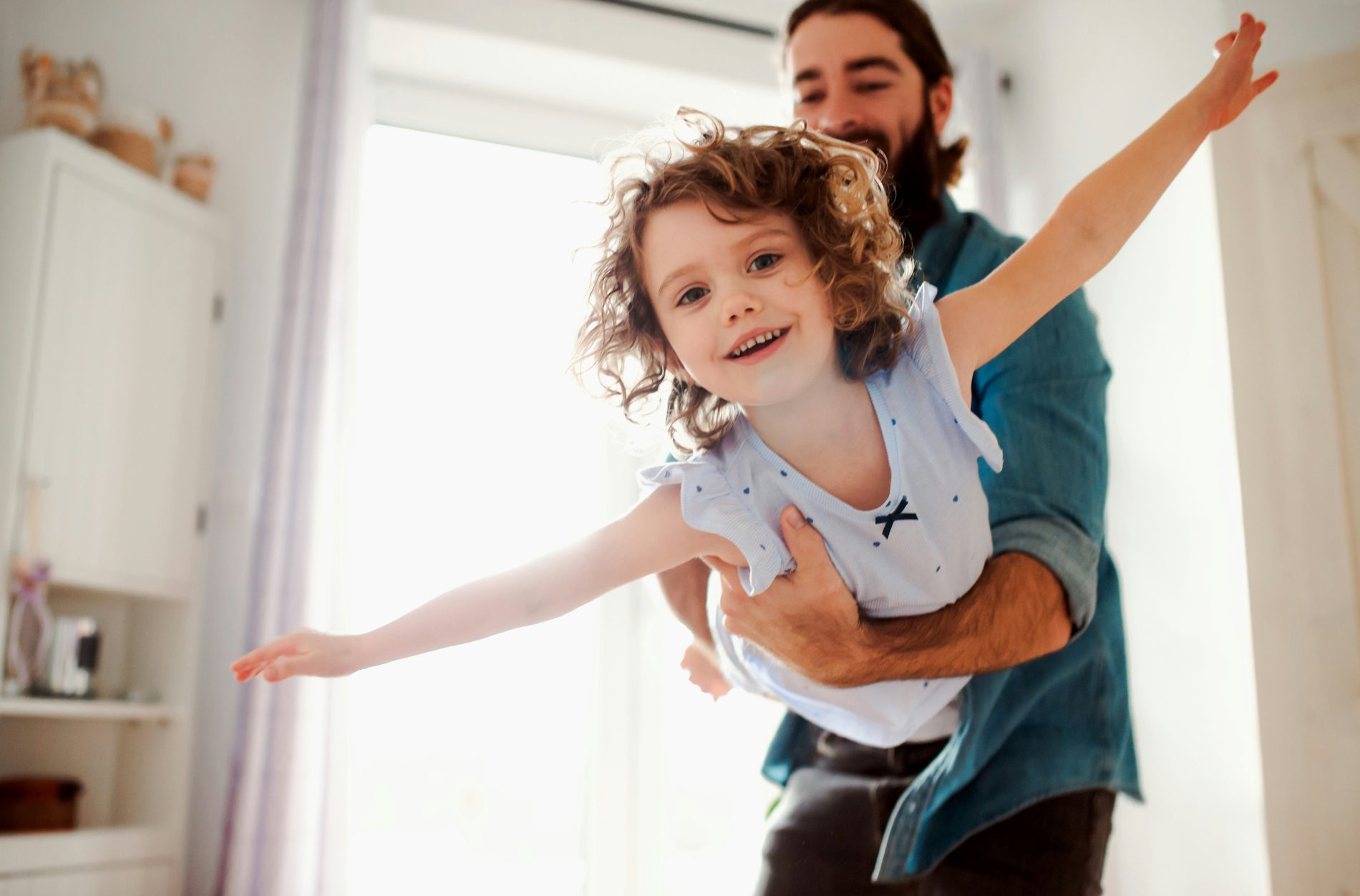 Father twirling his daughter in playful movement to help release big emotions in children and support emotional regulation.