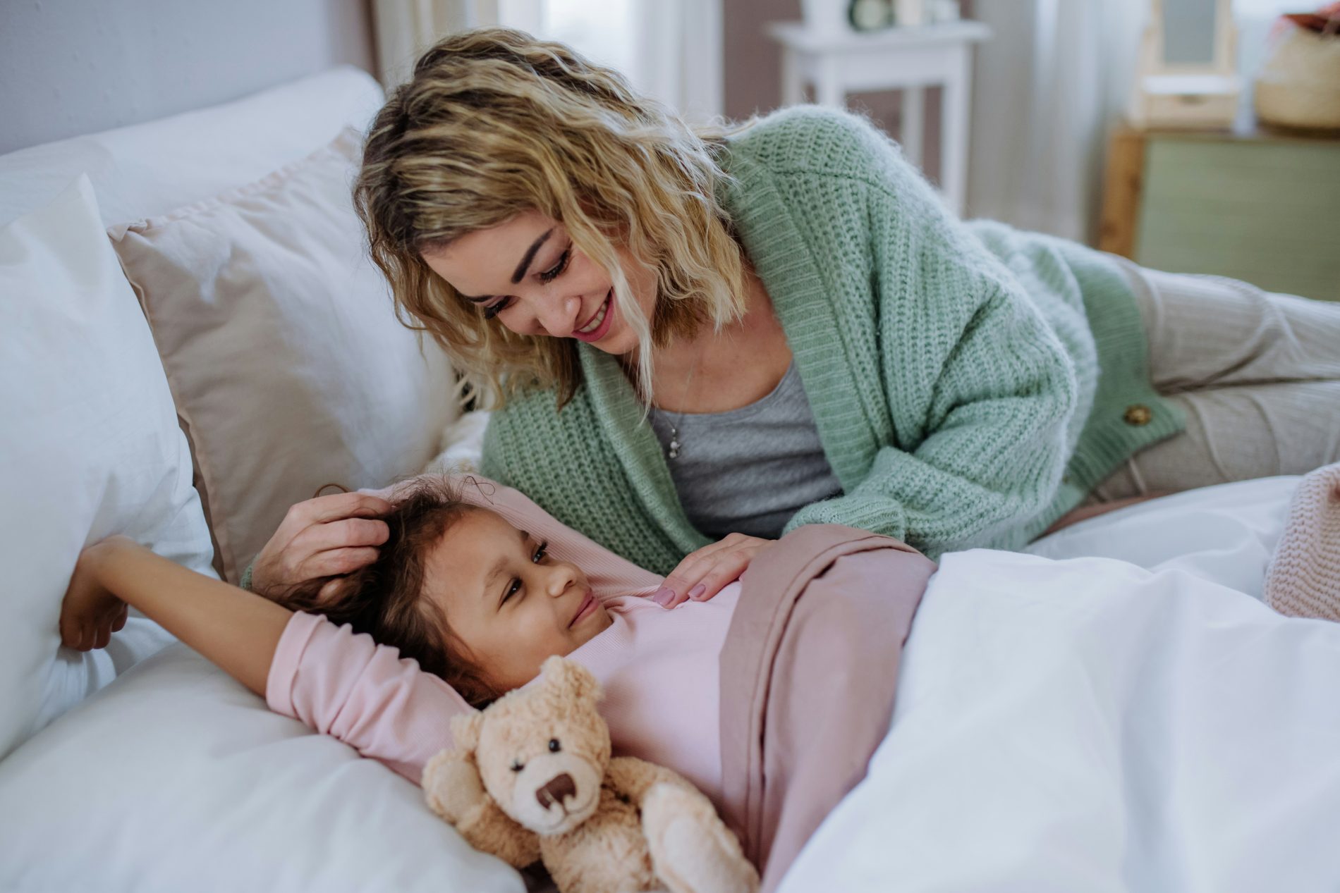 Mother gently comforting her tired child in bed, illustrating easing morning grogginess in children through calm connection