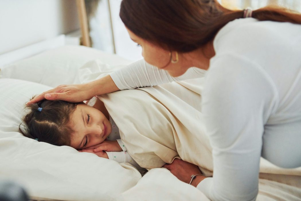 Parent gently soothing child in bed to ease bedtime resistance in children.