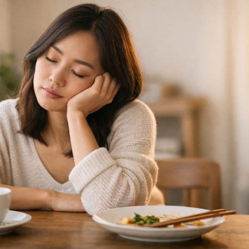 Woman feeling tired after eating, resting at table with tea in soft natural light